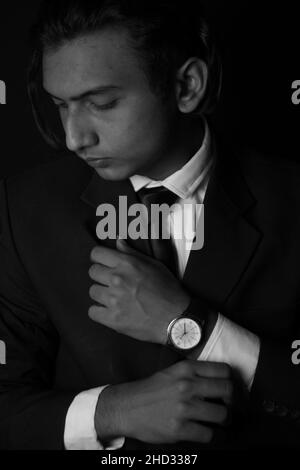 Vertical grayscale shot of an Indian man wearing a classy suit and watch Stock Photo