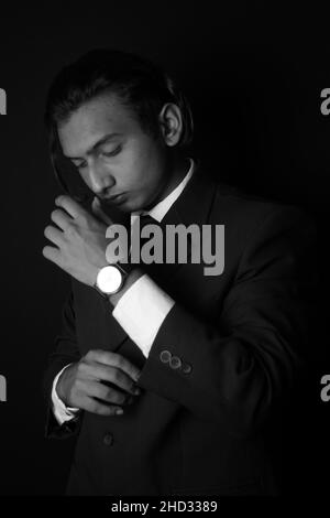 Vertical grayscale shot of an Indian man wearing a classy suit and watch Stock Photo