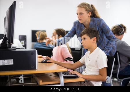 Teacher helping student with computer work Stock Photo