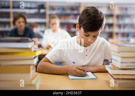 Young boy doing homework in library Stock Photo