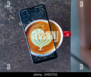 Top view of a transparent smartphone on a Cappuccino cup on a gray marble background Stock Photo