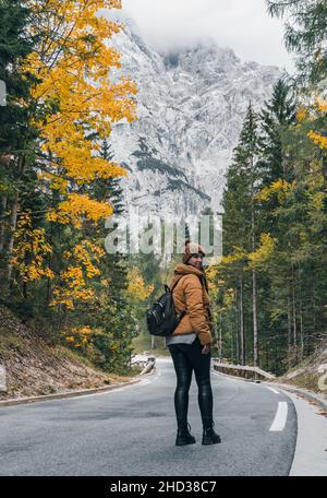 Vertical shot of a Caucasian female hiker on Vrsic mountain pass road in the Julian Alps, Slovenia Stock Photo