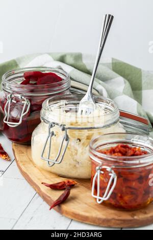 Jars of preserves on a wooden board with a fork in the sauerkraut in the middle. Stock Photo