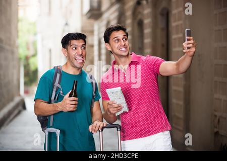Smiling friends walking with beer and making selfie Stock Photo