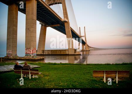 Lisbon, Portugal. 01st Jan, 2022. Two people sit near the Vasco da Gama bridge. Portugal records, since March 2020, 18,990 people have died in the national territory and 1,424,016 cases of SARS-CoV-2 virus infection have been identified, according to the General Health Department (DGS). Credit: SOPA Images Limited/Alamy Live News Stock Photo