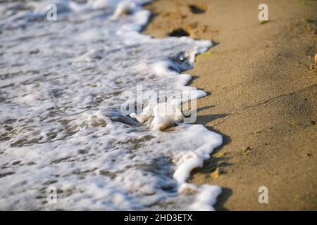 Shallow depth of field (selective focus) details with water covering footprints in the beach sand on a calm and warm summer day at the Black Sea in th Stock Photo