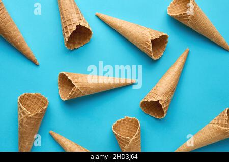 Empty ice cream waffle cones pattern on blue background. Summer food concept. Flat lay. Stock Photo