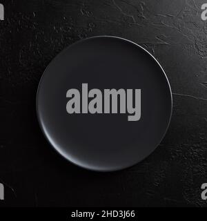 Empty round black plate on dark moody black background with copy space. Overhead top view. Stock Photo