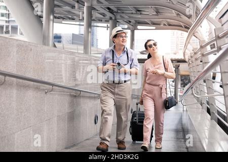 Senior Asian couple with a woman dragging a suitcase and talking happily with smiling at the airport to prepare to travel. Happiness of aunts and uncl Stock Photo