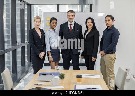 Business team standing in front of the meeting room. Successful company with happy in workers. Stock Photo
