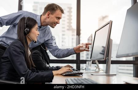 Assistant supervising the call center staff in the office. Manager assistant staffs in a call center. Customer service executive trainer assisting by Stock Photo