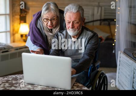 Happy senior couple using notebook at home and having fun together. Technology people concept Stock Photo