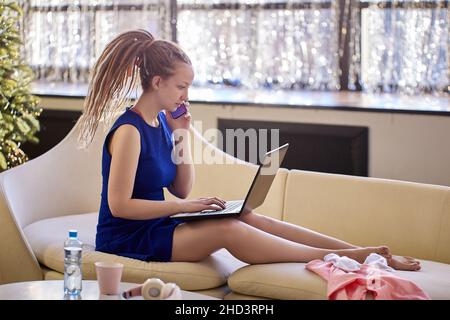 Live streaming classes by woman with handy and laptop indoors. Stock Photo