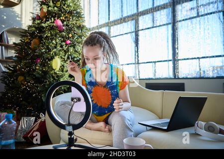 Live streaming by woman who uses laptop and ring light. Stock Photo