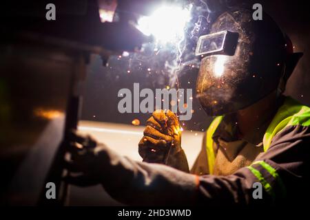 Man works on metal welding steel using electric welding machine to weld. Stock Photo