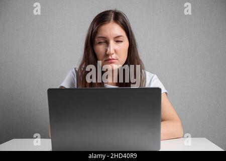 Woman with poor eyesight looks at laptop screen squinting Stock Photo