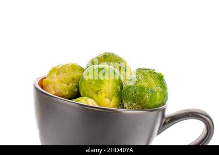 Several frozen organic Brussels sprouts in a ceramic bowl, close-up, isolated on white. Stock Photo