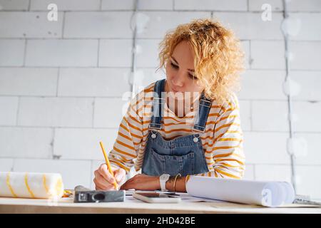 Low angle image of a female construction engineer working on a blueprint. Over a rough grey brick wall. Stock Photo
