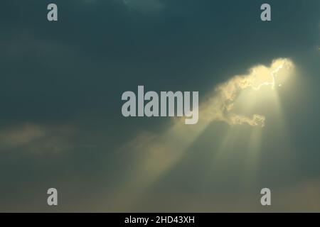 Sunlight Beaming Through the Grey Stormy Clouds with Sunrays Shining Down. Stock Photo