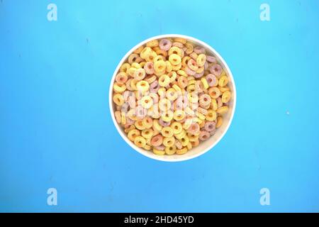 top view of colorful cereal corn flakes in a bowl on blue background  Stock Photo