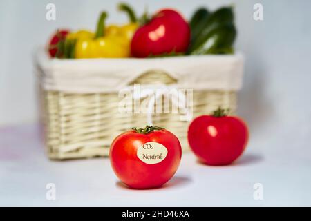 Carbon neutral product label on tomato. Carbon labeling. Basket of vegetables on background. Net zero carbon, emissions free. Organic farm products fr Stock Photo