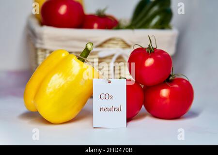Carbon neutral product label on tomatoes and yellow bell pepper. Carbon labeling. Basket of vegetables on foreground. Net zero carbon, emissions free. Stock Photo