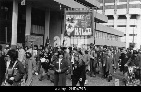 A 1984 demonstration march by members of the Southwark branch of the British trade union, NALGO (National and Local Government Officers' Association) protesting against the planned abolition of the GLC (Greater London Council). The photograph depicts the marchers passing by the IBM office building, Upper Ground, Southwark, London. The protestors are carrying the Southwark Branch NALGO banner and placards with the slogan, “Hands off Local Govt”. Stock Photo