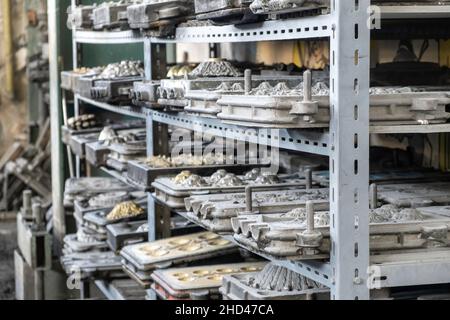 Metal molds for the production of various shapes of glass products lie on the shelves in the factory or glass manufacture. Stock Photo