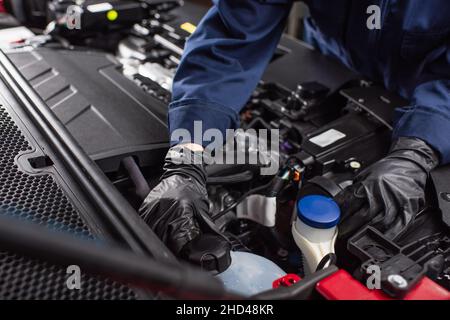 cropped view of mechanic in work gloves fixing engine of car Stock Photo