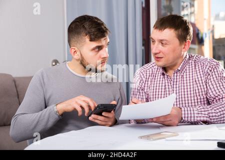 Serious males with documents and phone at home table Stock Photo