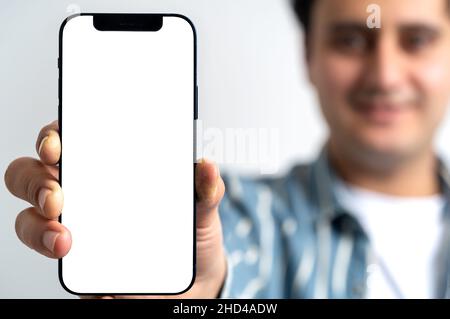 Young adult man showing mobile phone screen. screen mock up design. Selective focus. Stock Photo