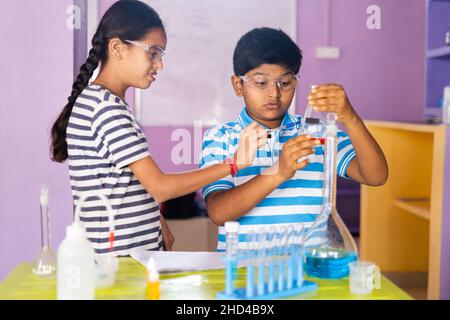 Close up shot of concentreted kids checking or analysing chimical by holding flask while doing experiment at chemistry laboratory Stock Photo