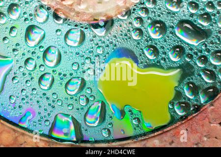 Closeup shot of water droplets and yellow paint on a CD surface Stock Photo