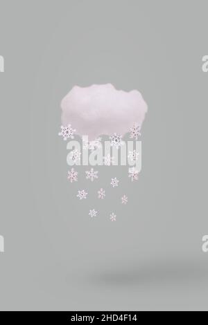 Creative weather concept with cloud and falling winter snowflake on gray background. Minimal winter holidays concept. Stock Photo