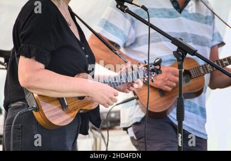 Male And Female Guitarists Playing Four String Wooden Ukuleles In A Band, Christchurch UK Stock Photo
