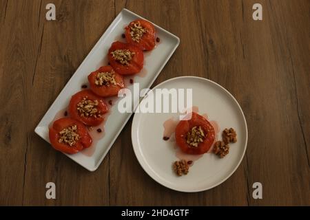 Quince dessert, oven baked quince  in thick syrup. White plate and wooden background. Food presentation concept and idea. Traditional Turkish cuisine. Stock Photo