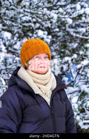 Middle aged woman outdoors in wintertime with snow-covered pine tree Stock Photo