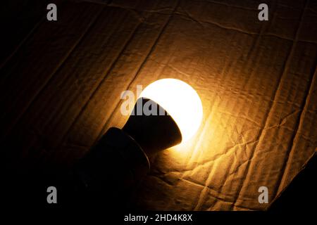 Yellow light bulb glows in the dark close up Stock Photo