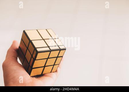 KORONADAL, PH – DEC 26, 2021: Rubik's Cube was invented by  Erno Rubik. Hand holding a completed gold irregular pattern of 3x3 rubik's cube puzzle. Stock Photo