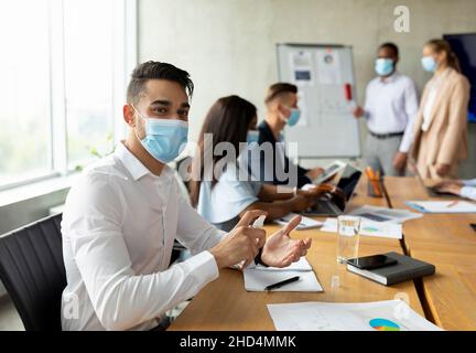 Workplace Safety. Arab Businessman Wearing Medical Mask Using Disinfectant Spray In Office Stock Photo