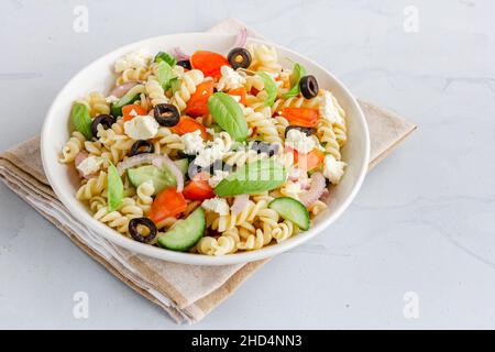 Fusilli Pasta Salad in a Bowl Garnished with Fresh Basil Leaves Close Up Photo Stock Photo