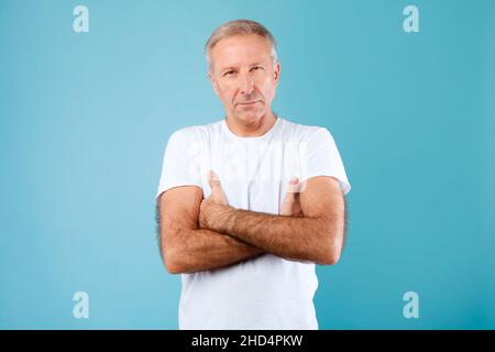 Serious mature man crossing arms posing at camera Stock Photo