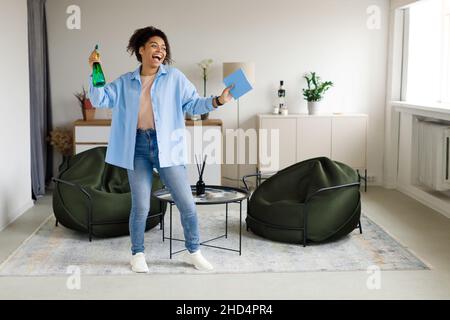 Portrait of black woman cleaning house singing holding rag Stock Photo