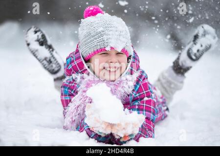 Happy girl throws snow. The child rejoices in winter and the first snow. Stock Photo