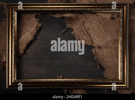 In a beautiful frame, a coarse weave fabric on a wooden background. Background for the inscription. Stock Photo