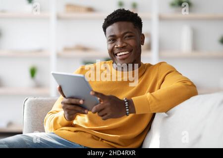 Happy black guy using digital tablet at home Stock Photo
