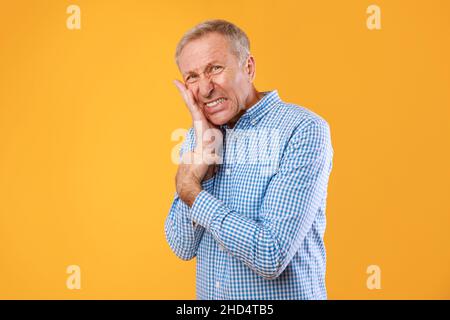 Portrait of unhappy mature man suffering from toothache Stock Photo