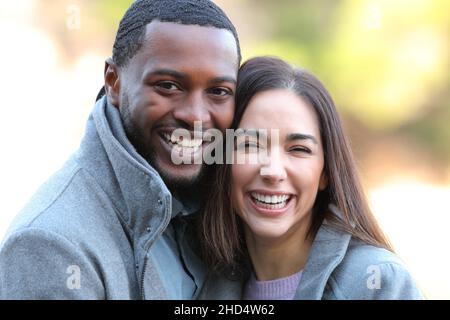 Happy interracial couple laughing with white teeth at camera in winter Stock Photo