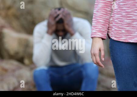 Caucasian woman leaving alone her sad boyfriend with black skin in a break up Stock Photo