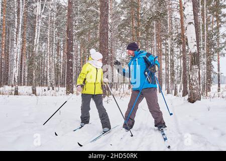 Quarrel of mature couple in winter sportswear are cross-country skiing in snowy forest. Stock Photo